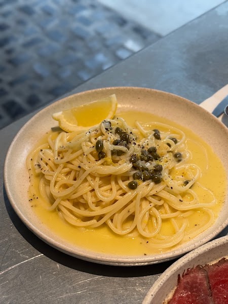 Lemon pasta with capers and citrus sauce served in a speckled ceramic bowl