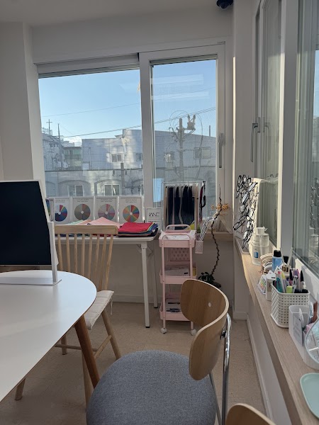 A sunlit office space with a desk, chairs, color charts, and accessories in a consultancy room.