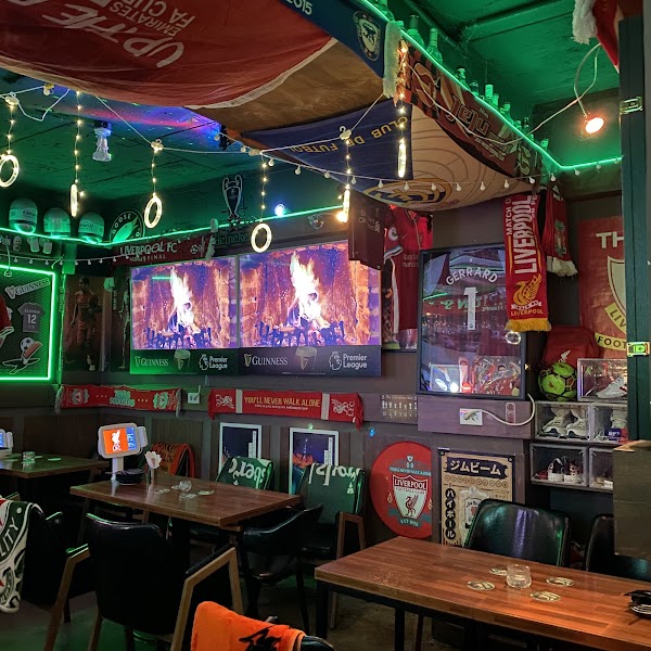 Interior of Liverpool Pub in Seoul, filled with football memorabilia and TVs displaying a fireplace