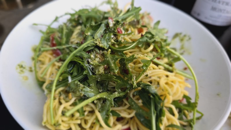 A bowl of pasta topped with fresh arugula in a wine bar