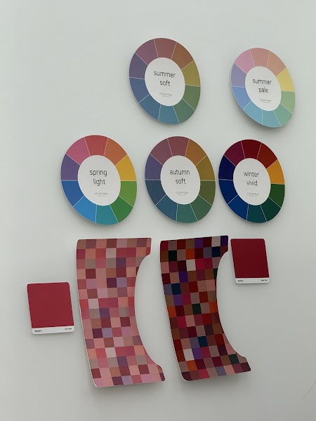 Color analysis charts and palette swatches displayed on a plain white wall at a consultancy studio.