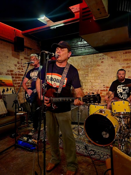Live band performance in front of a rustic exposed brick wall in the basement