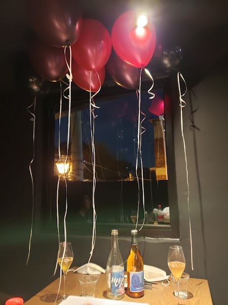 Wine bottles and glasses on a table under balloons in a dark wine bar at night