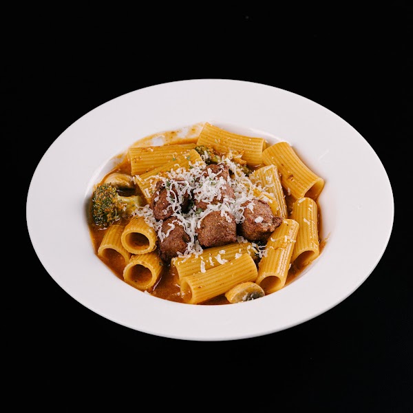 Rigatoni pasta with meatballs and broccoli in tomato sauce with grated cheese