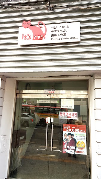 Exterior entrance of It's Me Photo Studio in Seoul with a sign featuring a pink cat logo.