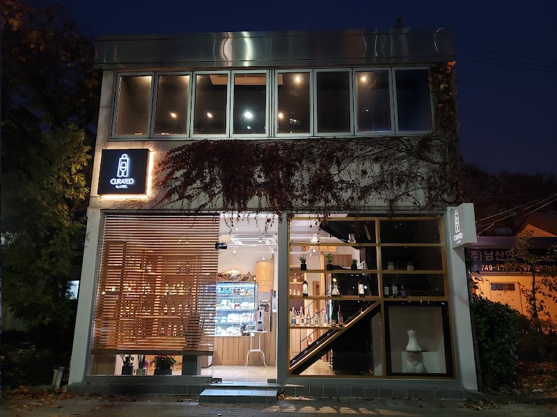 Exterior view of Curated by Label wine bar at night with glowing sign