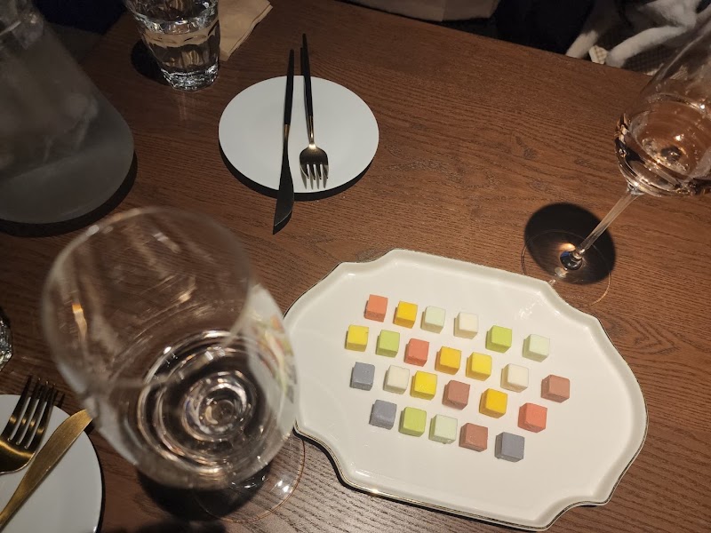 A plate of small colorful square snacks served on a dark wooden table in the wine bar
