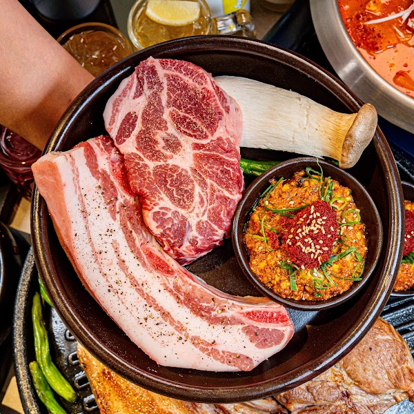 Fresh pork cuts with whole king oyster mushroom and house dipping sauce in ceramic bowl