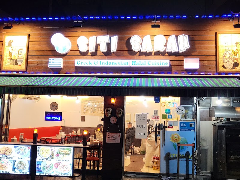 Exterior view of Siti Sarah restaurant with illuminated signage and menu displays at night.