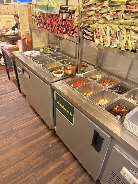 Side dish bar station with stainless steel food trays and instant noodle varieties