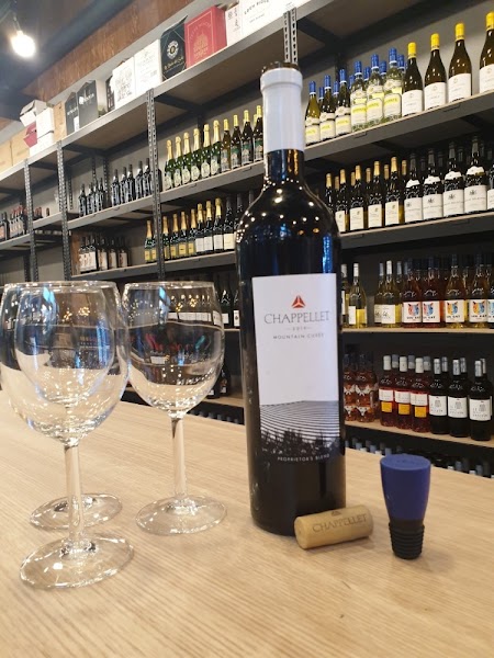 Bottle of red wine and tasting glasses on a wooden table inside the shop