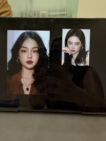 Two printed portraits of individuals with makeup on a screen surface