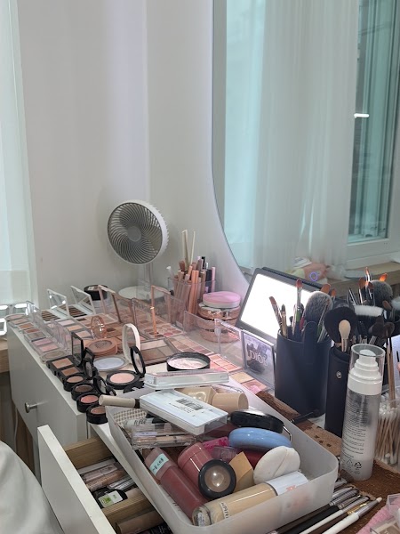 A professional makeup consultant workspace with organized palettes, brushes, and cosmetics on a white vanity table.