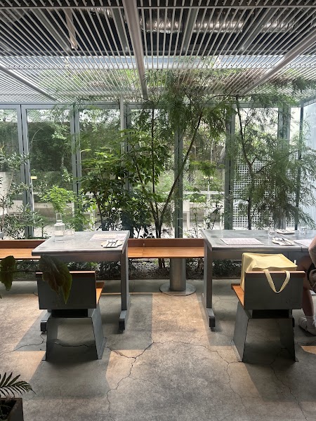 Bright garden-side dining area with industrial metallic tables and floor-to-ceiling glass windows at Natural High