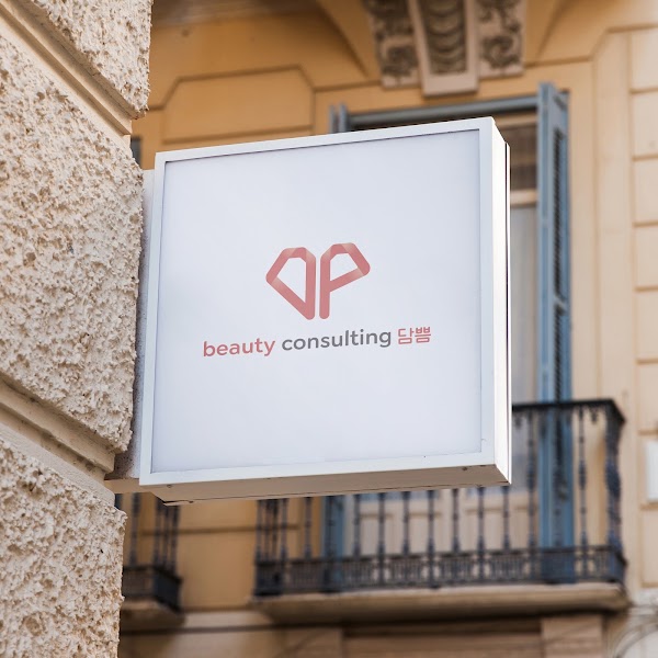 Square shop sign for a beauty consulting business mounted on a textured stone building wall