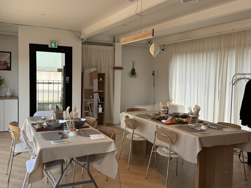 Interior of a bright, minimalist Korean cooking class studio with long tables set for preparation.