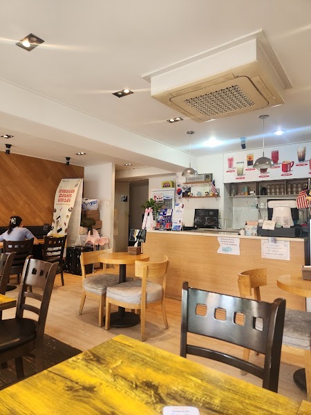 Warm interior dining area with light wood tables and service counter at Lepak Laa.