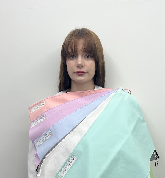 A person having a personal color analysis session with a fan of fabric swatches draped over their shoulders