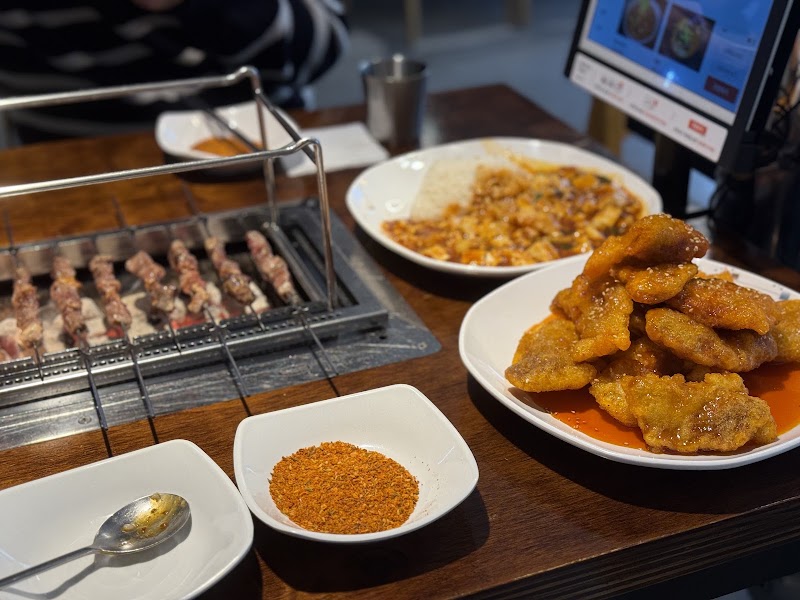 Table spread featuring lamb skewers on a charcoal grill alongside side dishes and specialties