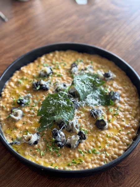 Creamy risotto with shellfish and fresh herbs served in a dark ceramic dish