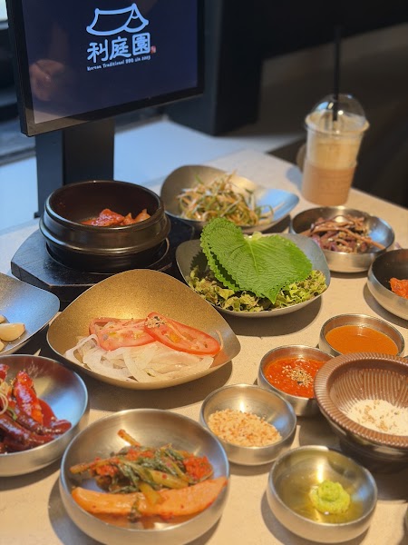 A variety of Korean side dishes served in metal bowls on a dining table at Lee Jung Won restaurant.