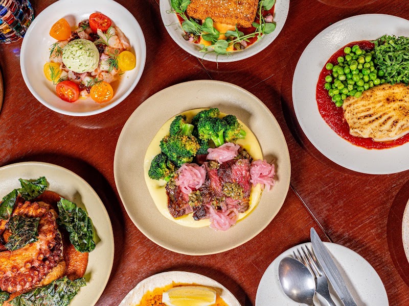 Overhead spread of shared tapas plates on a wooden dining table