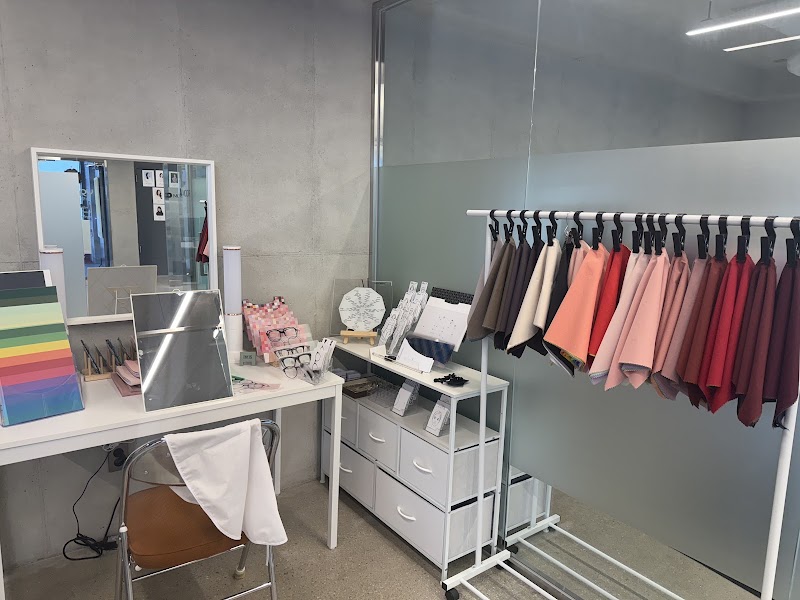 A personal color analysis consulting room with a desk, mirror, and a clothing rack filled with varied fabric color swatches.