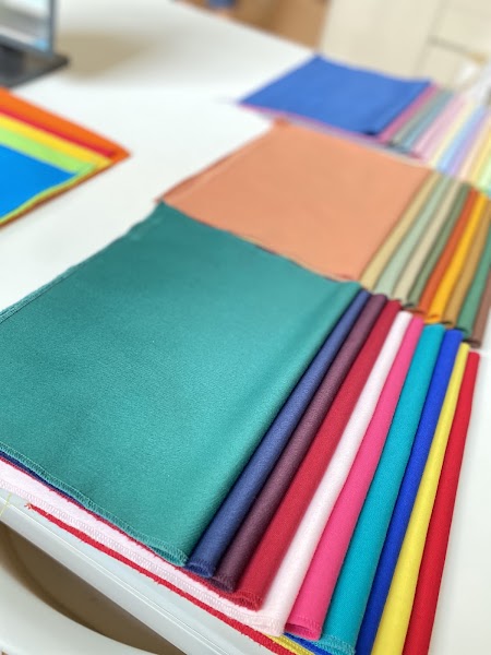 Detailed seasonal fabric swatches arrayed on white studio consulting desk