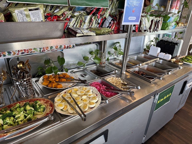 Self-service side dish station with plates of broccoli, seasoned vegetables, and boiled eggs