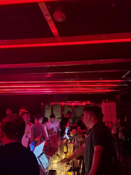 Interior of MICHIN SEOUL bar at night with red neon lighting, a busy bar counter, and patrons