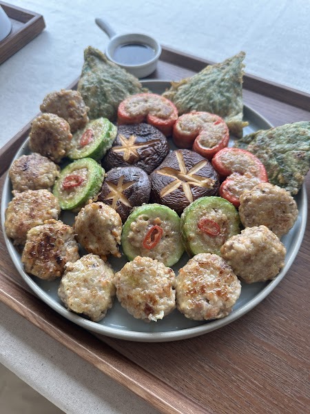 A plate of assorted Korean-style meat and vegetable fritters arranged on a wooden tray.