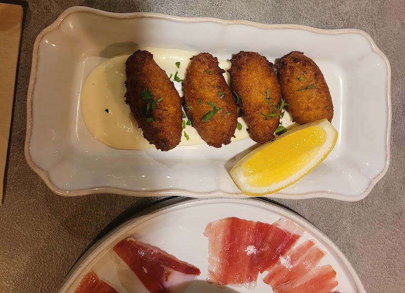 Golden-brown fried croquettes served with lemon wedge on a rectangular plate