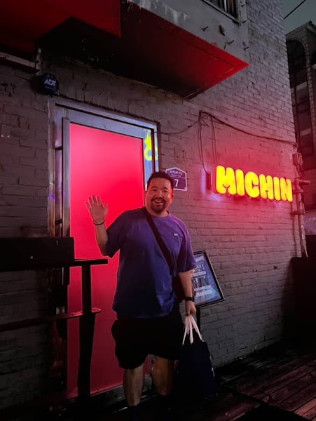 Entrance of MICHIN bar in Seoul at night with a person waving in front of a red illuminated door
