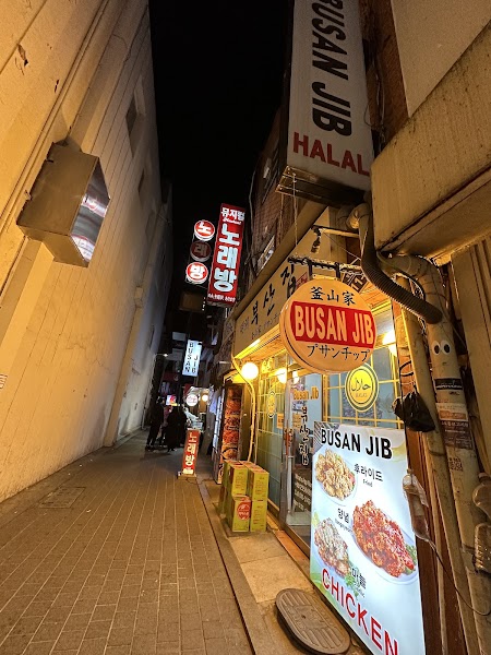 Exterior storefront of Busan Jib restaurant at night in a narrow alley in Myeongdong, Seoul