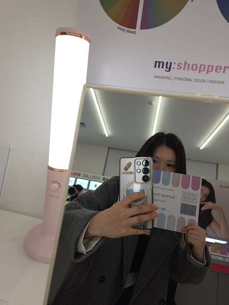 Client checking personal color palette card in studio mirror