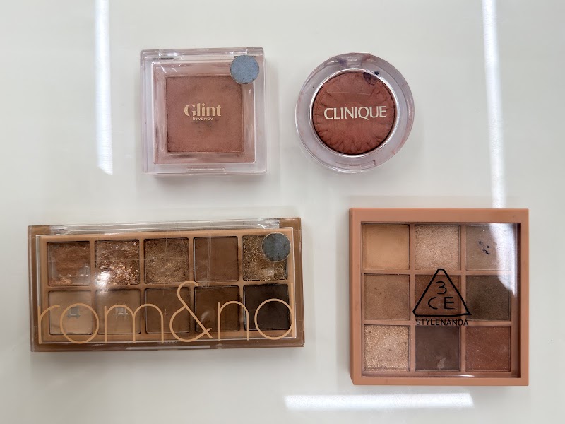 Curated neutral-toned eyeshadow and blush compacts arranged on white consultation table