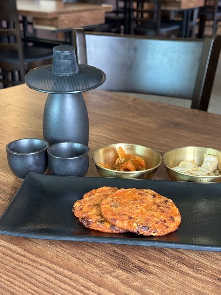 Table setting at de mitt featuring golden pan-fried dishes on black textured plates with brass side bowls