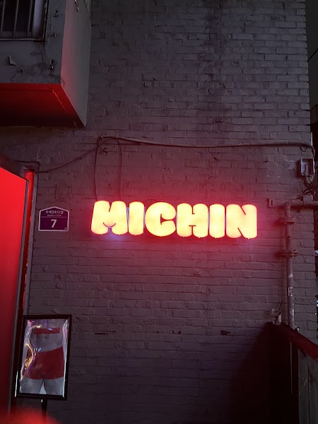 Neon MICHIN sign on a brick wall at night