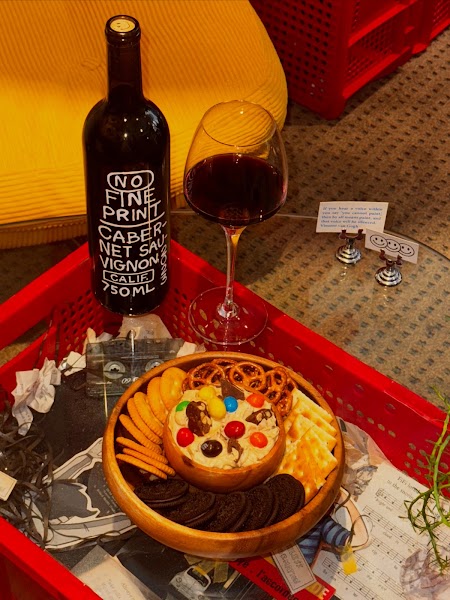 Bottle of wine, stemmed wine glass, and savory snack assortment