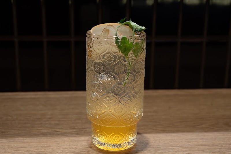 Craft house cocktail served in an embossed crystal glass with pear slice and fresh herbs