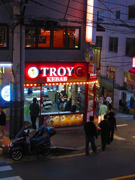 Exterior view of Troy Kebab shop in Seoul at twilight with red signage