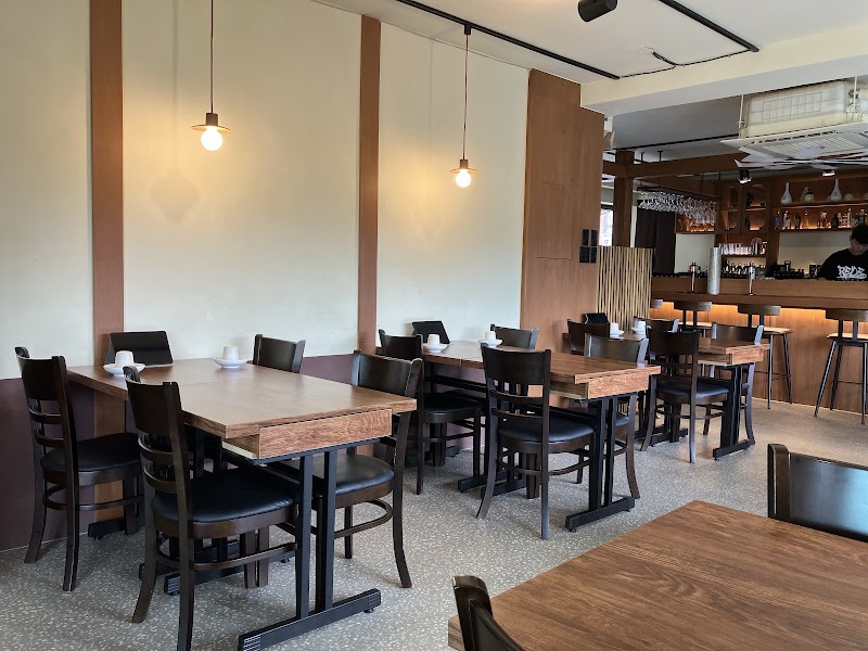 Minimalist dining room with warm wood tables, comfortable black chairs, and soft pendant lighting at de mitt