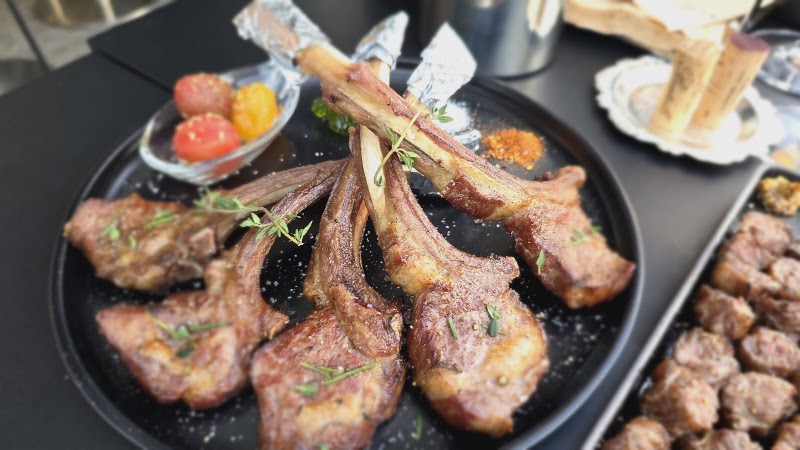 A platter of grilled lamb chops garnished with herbs and side vegetables