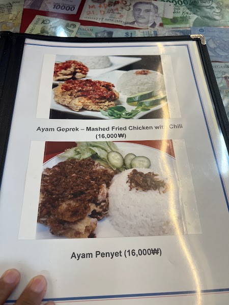 A physical menu page from Siti Sarah restaurant showing two Indonesian chicken dishes with rice and cucumber slices.