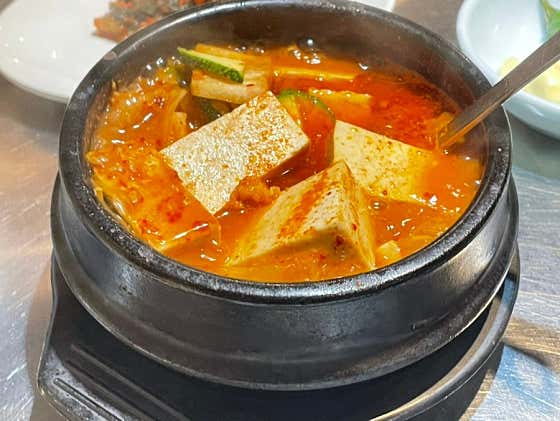 Bubbling hot clay pot stew with tofu, kimchi, and zucchini
