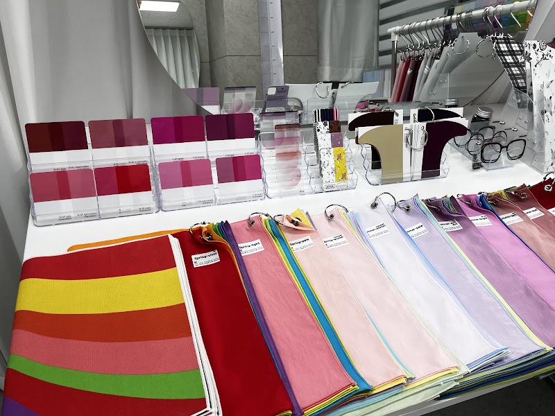 Collection of personal color analysis fabric drapes and color swatch cards on a white table in a studio.