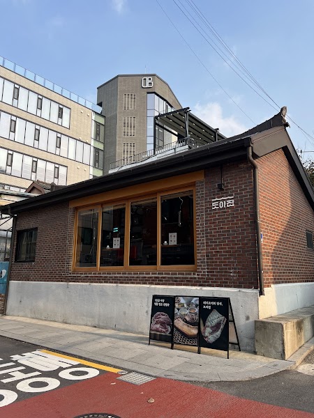 Exterior view of Doyajib Korean BBQ restaurant in Seoul with a red brick facade and sidewalk menu signage