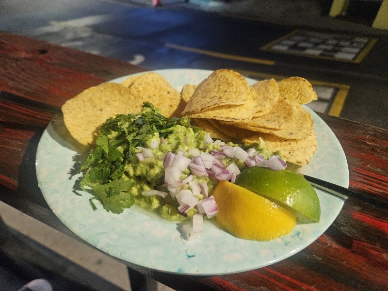Fresh house guacamole with tortilla chips, cilantro, diced red onions, and lime wedges at Gitana