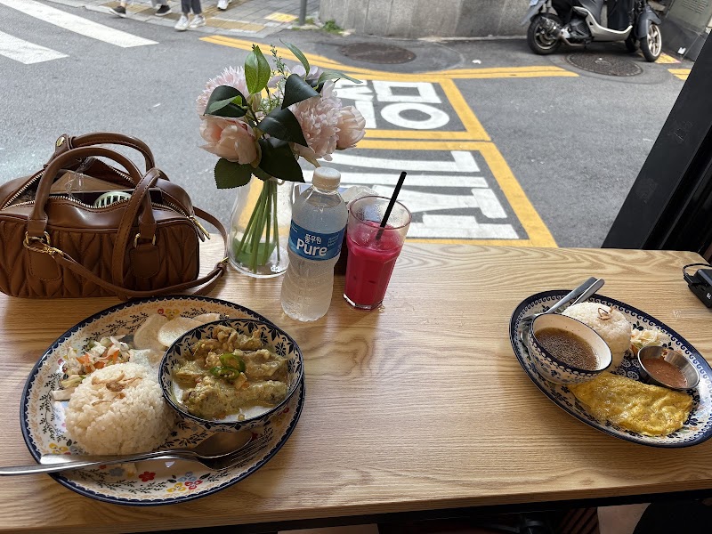 Plates of meals and drinks set beside the street-view window at Lepak Laa Restaurant.