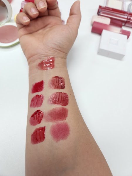 Swatches of various shades of lip cosmetic products applied to a human forearm